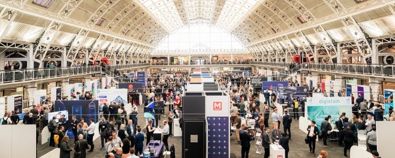 Image is a photo of a previous Showcase, showing great attendance and lots of stalls for people to visit