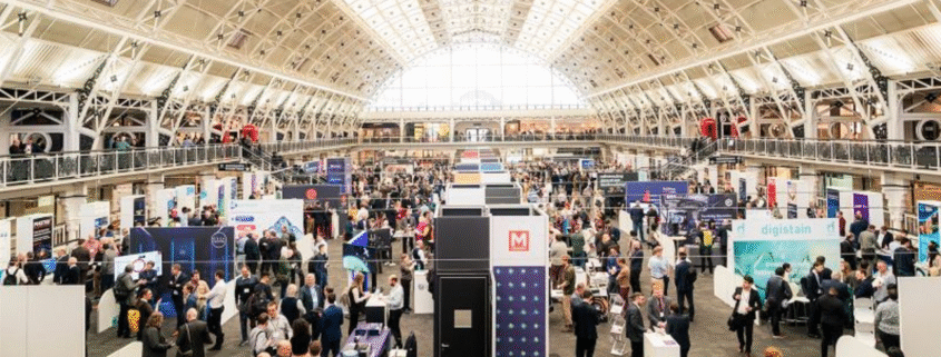 Image is a photo of a previous Showcase, showing great attendance and lots of stalls for people to visit